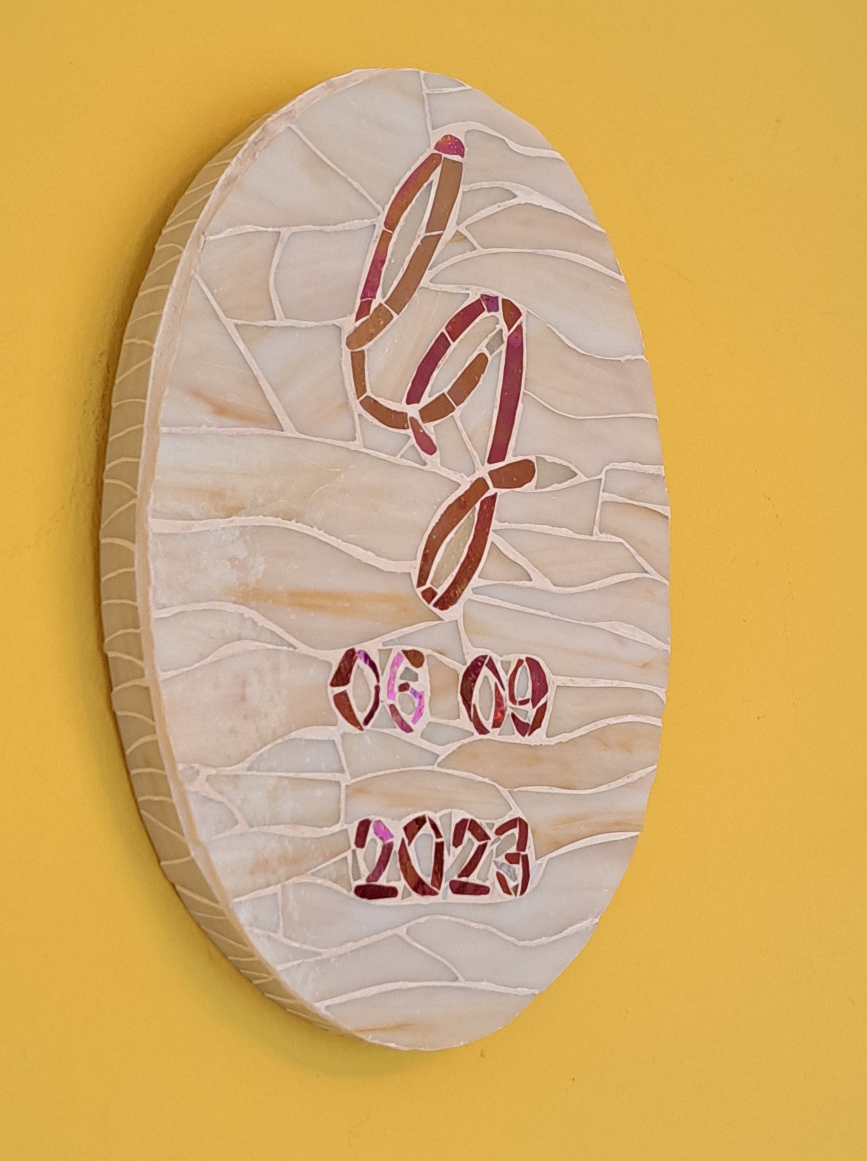 An oval base upon which red glass spells out the couple's initials wedding date. The main body of the work features creamy glass set in a wispy pattern.